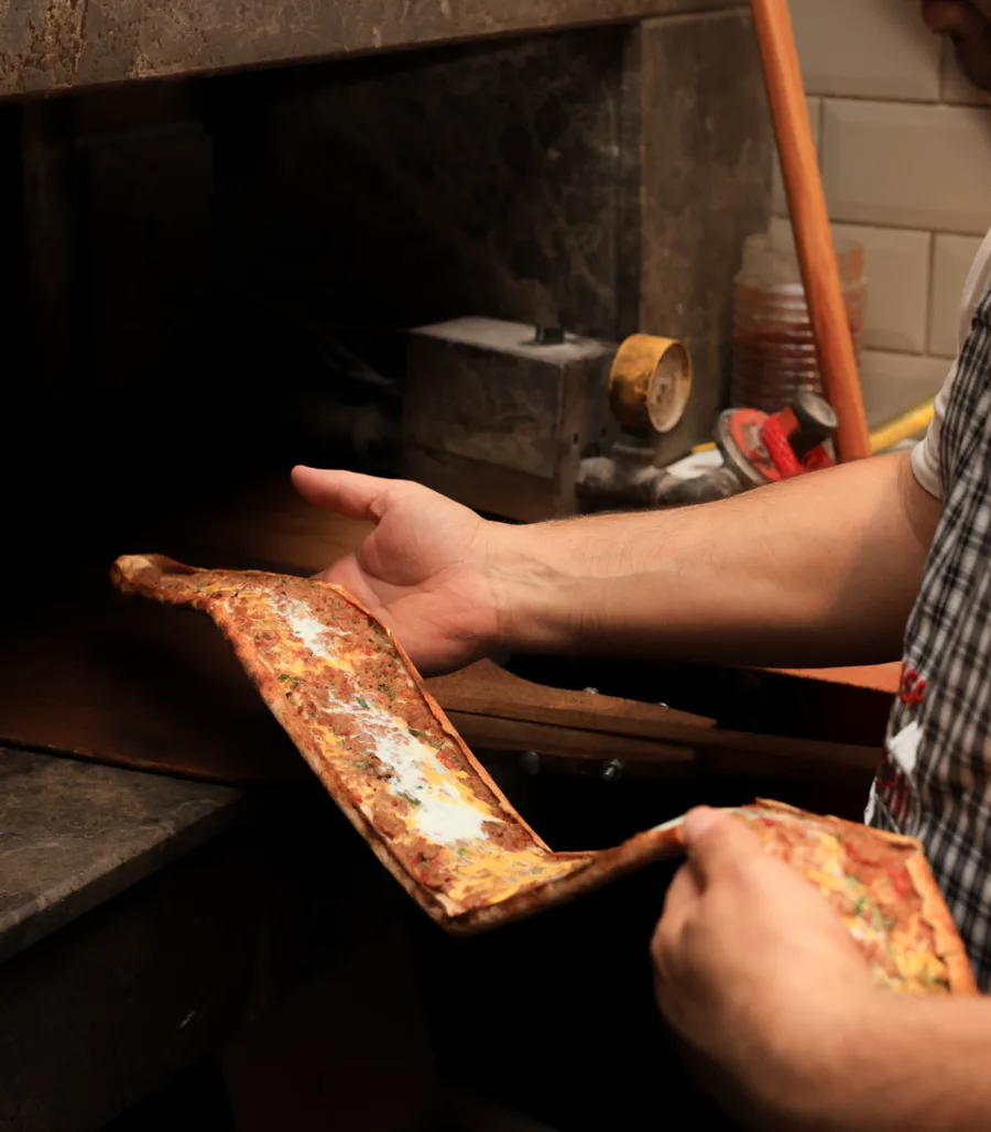 Usta, kıymalı yumurtalı pideyi taş fırından çıkarıyor